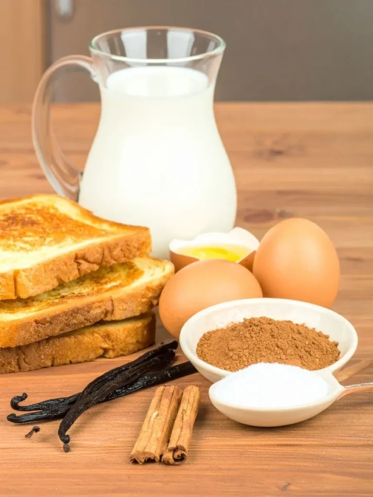Ingredients laid out for making French Toast Waffle Hybrid including bread, eggs, milk, cinnamon, and vanilla